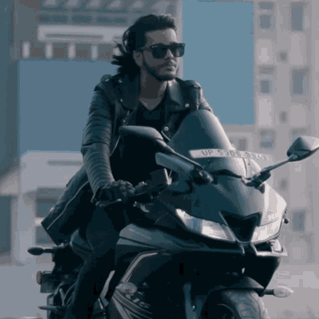 a man wearing sunglasses is riding a black motorcycle with a license plate that says up 5308 3kx