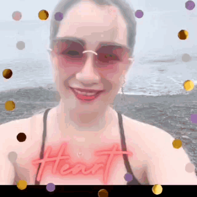 a woman wearing sunglasses and a necklace has the word heart on her chest