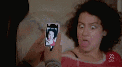 a woman is taking a selfie with a cell phone .