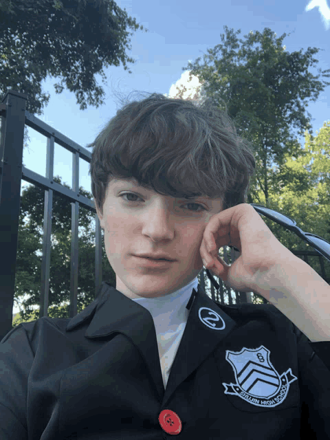 a person wearing a black jacket with a red button that says ' southern high school ' on the sleeve