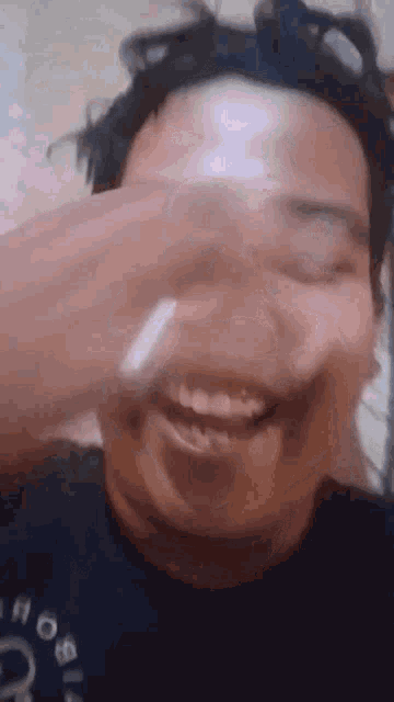 a man is covering his face with his hand while smiling .