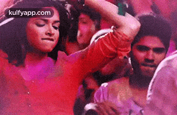 a man and a woman are dancing in a crowd of people at a party .