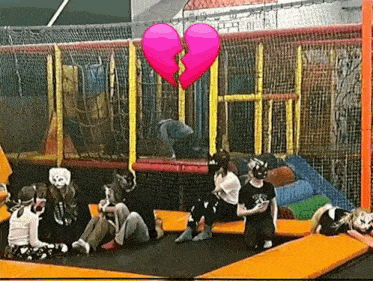 a group of people are sitting on a trampoline with a broken heart .