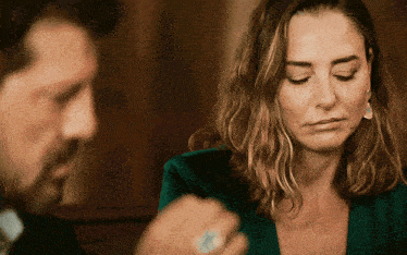 a man and a woman are sitting at a table and the woman is wearing earrings