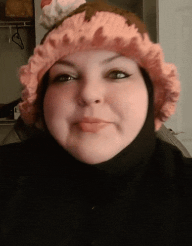 a woman wearing a pink hat with a cupcake on top of it