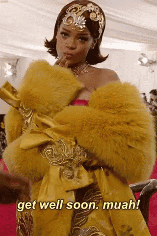 a woman in a yellow fur coat is standing on a red carpet and says get well soon muah .