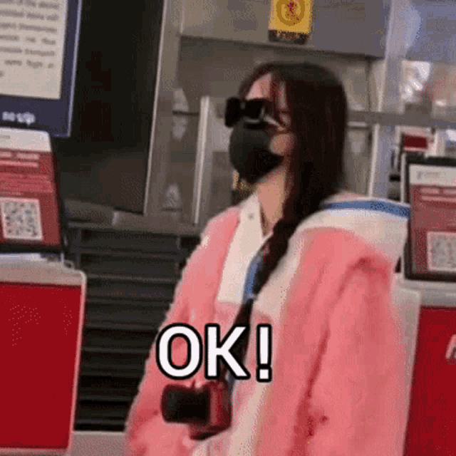 a woman wearing a mask and sunglasses is holding a camera and says ok !