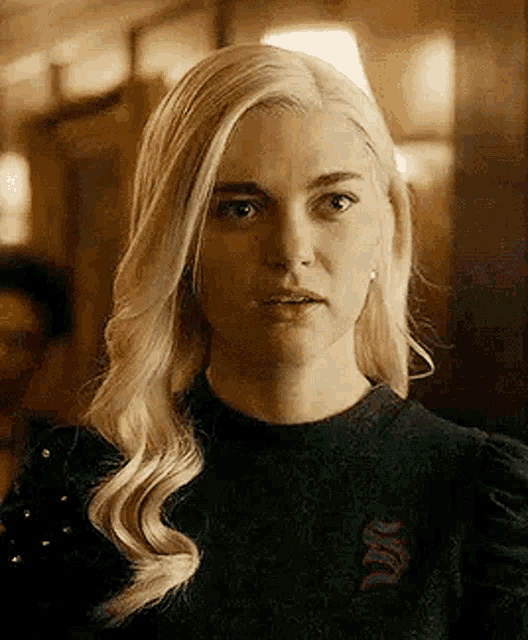 a close up of a woman with blonde hair wearing a black shirt and earrings .