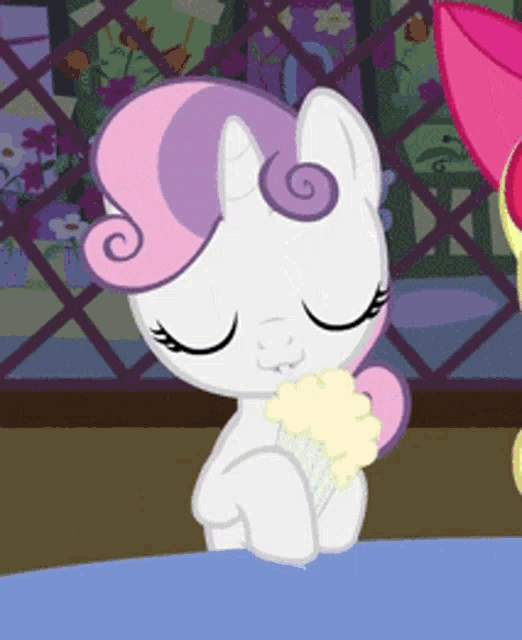 a white pony with a pink mane is eating a cone of ice cream