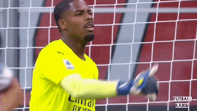 a soccer goalie wearing a yellow jersey and blue gloves