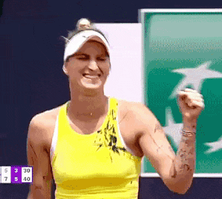 a woman wearing a yellow tank top and a white hat is holding her fist up in the air