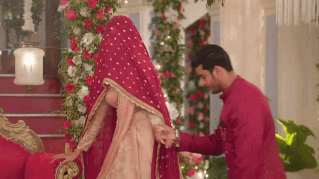 a man in a red shirt helps a woman with her dress