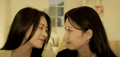 two young women are looking at each other with their eyes closed