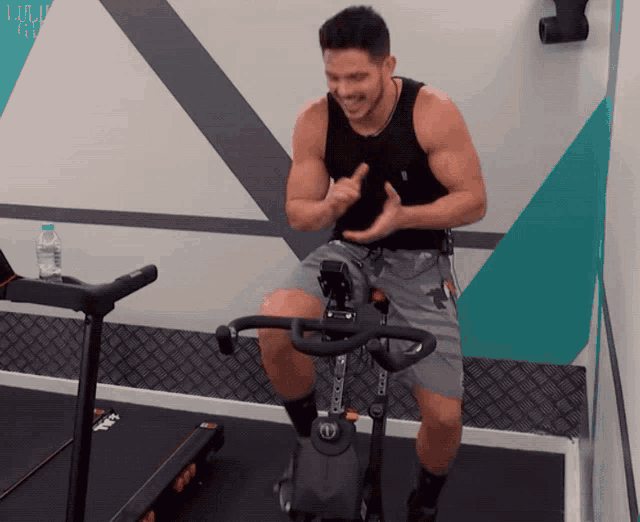 a man riding an exercise bike in a gym with a bottle of water in the background
