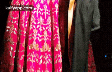 a woman is wearing a pink dress and a man is wearing a black suit .