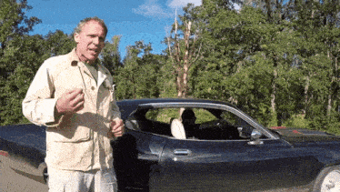 a man is standing next to a black car with the door open