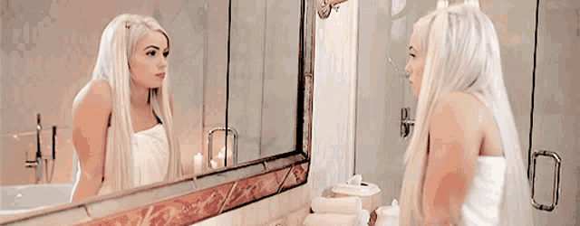 a woman wrapped in a towel is looking at herself in the mirror