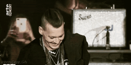 a man is laughing in front of a screen that says arte concert on it