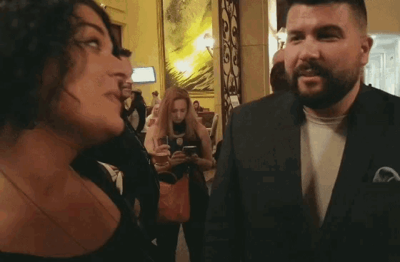 a man in a suit talks to a woman in a crowd
