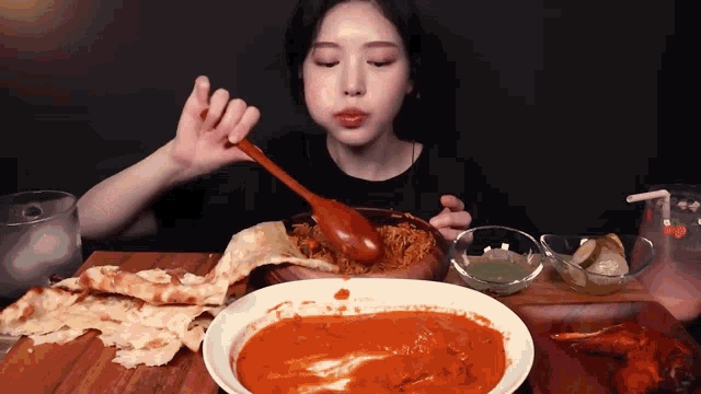 a woman is eating a bowl of food with a spoon in her mouth