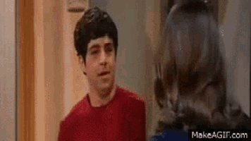 a man in a red shirt is standing next to a woman in a blue shirt and they are looking at each other .