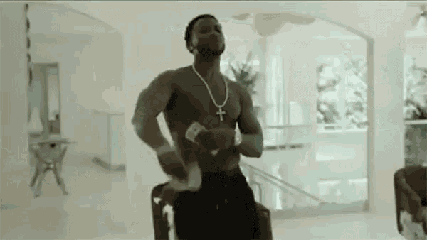 a shirtless man is dancing in a living room while holding a stack of money .
