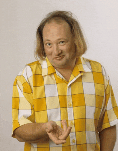 a man wearing a yellow and white plaid shirt holds his hand out