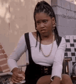 a woman with braids is sitting in a chair holding a bottle of beer