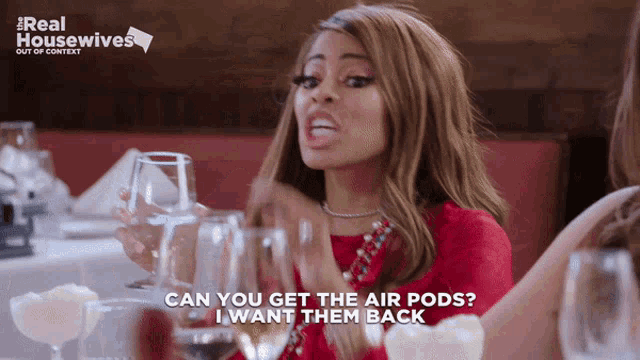 a woman sitting at a table with wine glasses says " can you get the air pods "