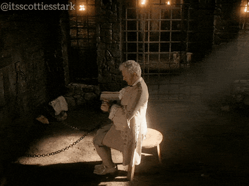 a man in a white coat is chained to a chair in a dark room with the hashtag itsscottiesstark