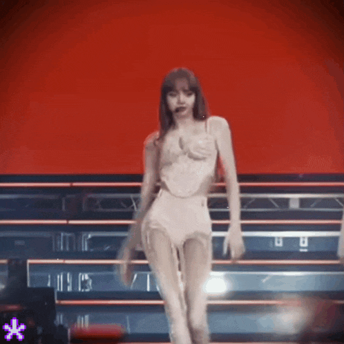 a woman in a white dress is dancing on a stage in front of a red background .