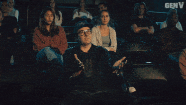 a group of people are sitting in a theater with genv written on the bottom