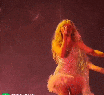 a woman in a pink dress is holding a microphone on a stage .
