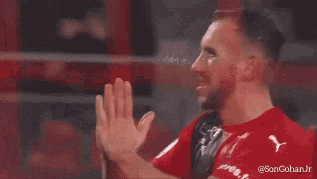 a man wearing a red puma shirt is clapping