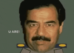 a man with a mustache and a military uniform is making a funny face .