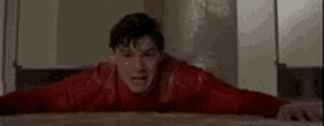 a man in a red sweater is crawling on the floor in a room .