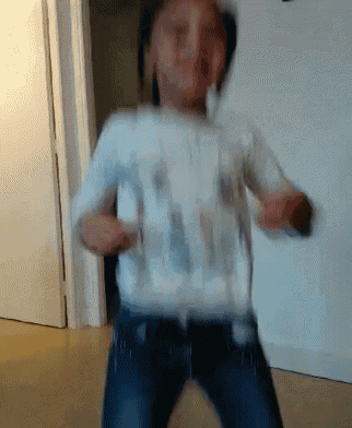 a young girl in a white shirt and blue jeans is dancing in a room