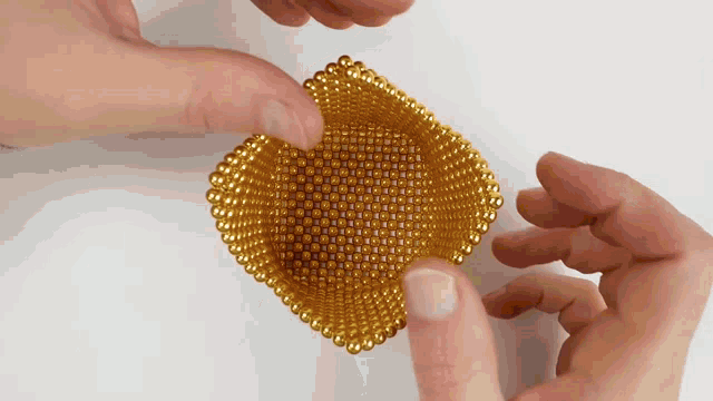 a person is holding a gold colored object with their hands