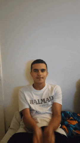 a young man wearing a white balmain paris t-shirt