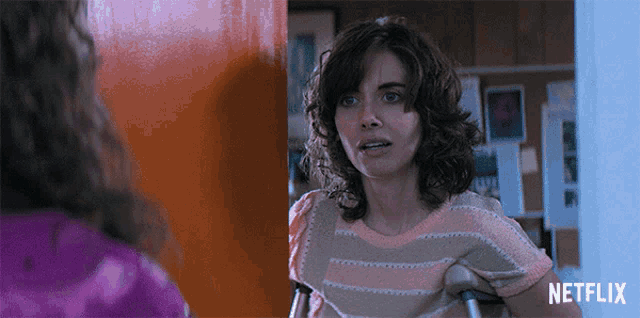 a woman with crutches is standing in front of a door that says netflix