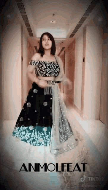 a woman in a black and white dress is dancing in a hallway with the words anmolfeat written on the bottom