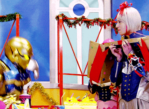 a woman is holding a gift box in front of a statue of a man