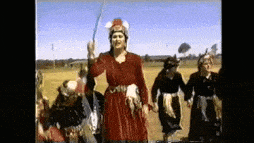 a woman in a red dress is holding a sword in front of a group of people