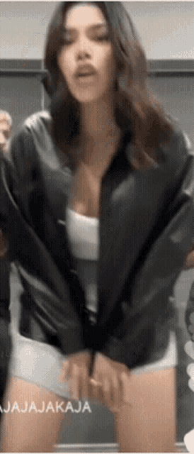 a woman wearing a black jacket and shorts is dancing with the words jajajakaja in the corner .