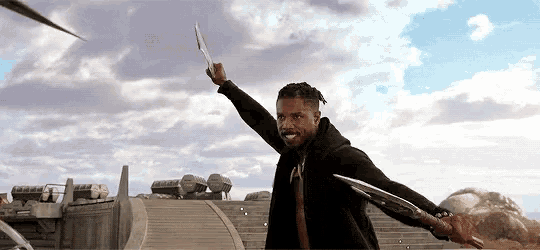 a man in a black jacket is holding two swords in his hands .