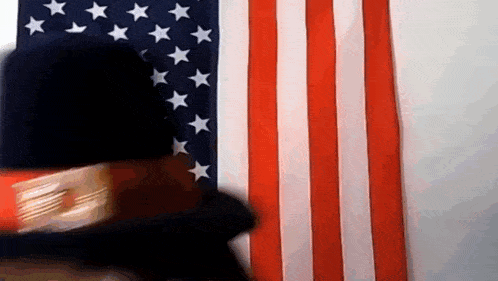 a man wearing a top hat stands in front of an american flag