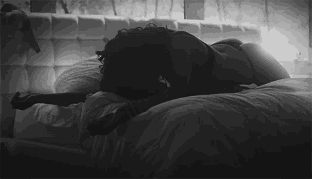 a woman in lingerie is laying on a bed with her head down .