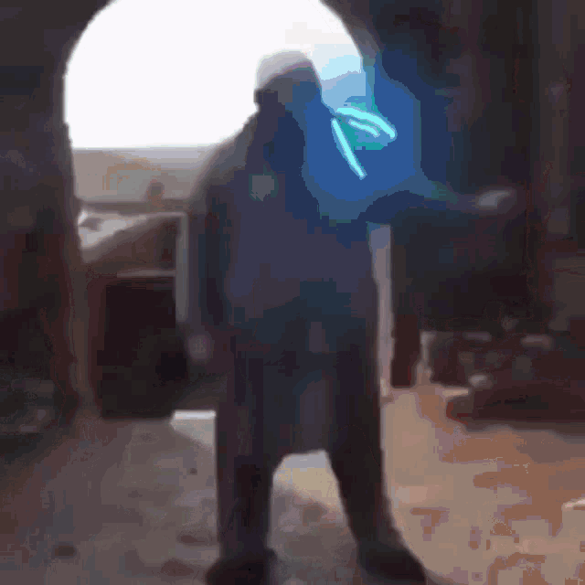a blurry picture of a man standing in a room with a blue light behind him