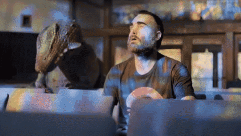 a man with a beard looks up at a dinosaur statue