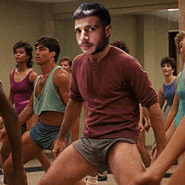 a man in a maroon shirt stands in front of a group of women